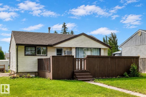 Exterior featuring horizontal vinyl siding, brown wood deck with steps, a shingled roof, and a concrete pathway - 50 Rocque, Fort Saskatchewan, AB - Outdoor