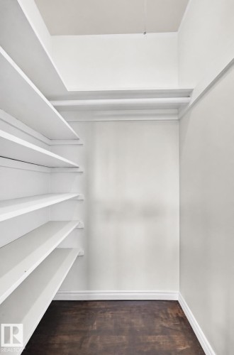 Built-in shelving, dark wood-finish flooring, and white painted walls - 50 Rocque, Fort Saskatchewan, AB - Indoor With Storage