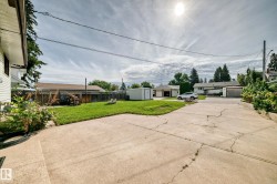 Expansive concrete driveway, manicured lawn, and wooden privacy fence - 