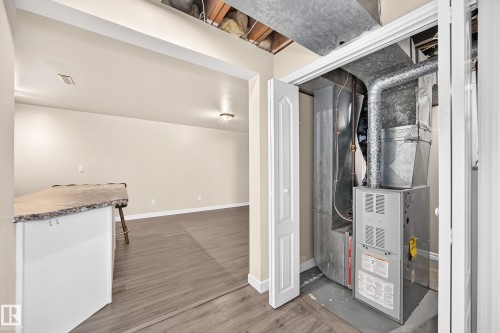 Utility closet with HVAC system, finished room featuring wood-finish flooring, light-colored walls, and a built-in counter with a textured surface - 50 Rocque, Fort Saskatchewan, AB - Indoor