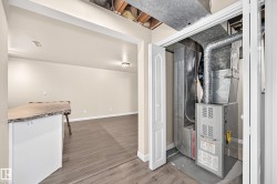 Utility closet with HVAC system, finished room featuring wood-finish flooring, light-colored walls, and a built-in counter with a textured surface - 