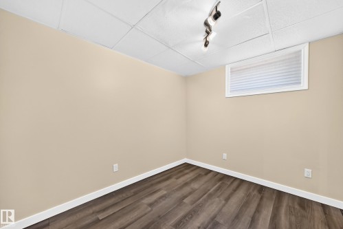 Wood-finish flooring with white baseboards, light-toned walls, and a drop ceiling with track lighting - 50 Rocque, Fort Saskatchewan, AB - Indoor Photo Showing Other Room
