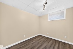 Wood-finish flooring with white baseboards, light-toned walls, and a drop ceiling with track lighting - 