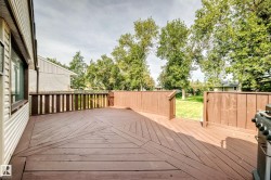Expansive wood deck with a patterned floor design, wood railing, and direct access to a grassy yard - 