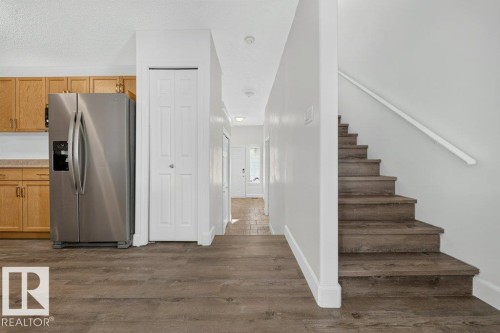 Wood-finish flooring throughout, with a wood-finish staircase and white handrail - #47 30 Levasseur Rd, St. Albert, AB - Indoor Photo Showing Other Room