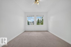 Neutral carpeted flooring, white painted walls, and a ceiling-mounted light fixture with fan - 