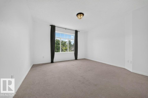 Recessed window with exterior scenery, overhead decorative light fixture, textured ceiling, and carpeting - #47 30 Levasseur Rd, St. Albert, AB - Indoor Photo Showing Other Room