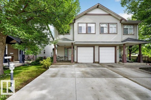 Two-story siding exterior with multiple windows, dual garage doors, and covered entryway - #47 30 Levasseur Rd, St. Albert, AB - Outdoor With Facade
