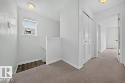 Bright upper-level hallway featuring neutral carpeting, white painted walls, and recessed ceiling lighting - 
