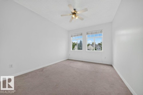 Carpeted flooring, white walls, two windows, and a ceiling fan with integrated lighting - #47 30 Levasseur Rd, St. Albert, AB - Indoor Photo Showing Other Room