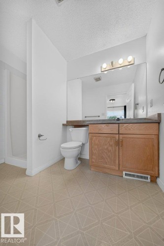 Wood-finish vanity with dual-door cabinetry, a full-width mirror, and overhead vanity lighting - #47 30 Levasseur Rd, St. Albert, AB - Indoor Photo Showing Bathroom