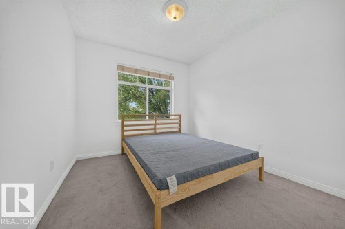 Light-colored wall-to-wall carpeting, white painted walls, and a multi-pane window - #47 30 Levasseur Rd, St. Albert, AB - Indoor Photo Showing Bedroom