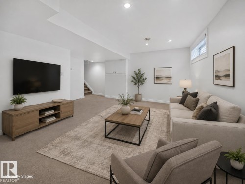 Recessed lighting illuminates this carpeted living space with a wood-finish media console - #47 30 Levasseur Rd, St. Albert, AB - Indoor Photo Showing Living Room