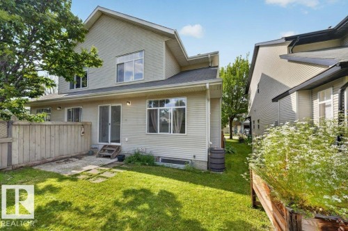 Expansive rear yard featuring green lawn, a concrete patio area, and a wood privacy fence - #47 30 Levasseur Rd, St. Albert, AB - Outdoor With Exterior