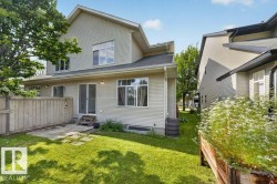 Expansive rear yard featuring green lawn, a concrete patio area, and a wood privacy fence - 