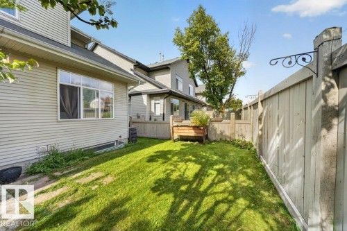 Fenced backyard featuring a manicured lawn, established trees, and a raised planter box - #47 30 Levasseur Rd, St. Albert, AB - Outdoor