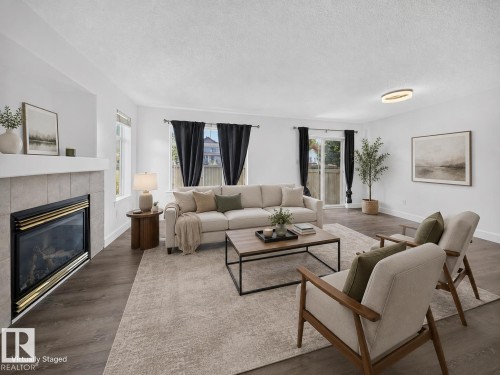 Living area featuring wood-finish flooring, a tiled fireplace, and white walls - #47 30 Levasseur Rd, St. Albert, AB - Indoor Photo Showing Living Room With Fireplace