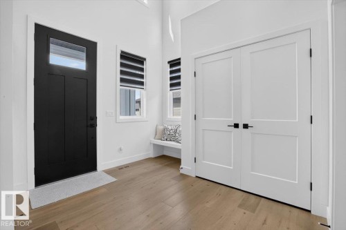 Front entry with a dark-paneled door, transom window, and wood-finish flooring - 94 Harvest Crescent, Ardrossan, AB - Indoor Photo Showing Other Room