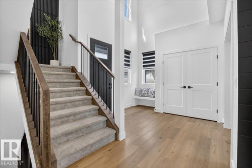 Carpeted staircase with wood-finish handrail and black metal balusters - 94 Harvest Crescent, Ardrossan, AB - Indoor Photo Showing Other Room