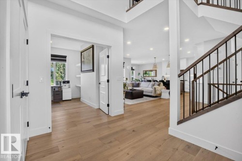 Wood-finish flooring throughout, white walls, and a staircase with dark wood-finish handrails and black metal balusters - 94 Harvest Crescent, Ardrossan, AB - Indoor Photo Showing Other Room