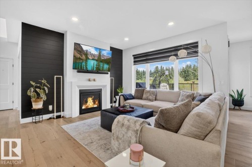 Living area featuring wood-finish flooring, a white mantel, a black shiplap accent wall, recessed lighting, and large windows - 94 Harvest Crescent, Ardrossan, AB - Indoor Photo Showing Living Room With Fireplace