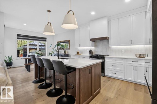 Kitchen featuring white shaker cabinetry, an island with wood-finish paneling, light wood-finish flooring, and white countertops - 94 Harvest Crescent, Ardrossan, AB - Indoor Photo Showing Kitchen With Upgraded Kitchen