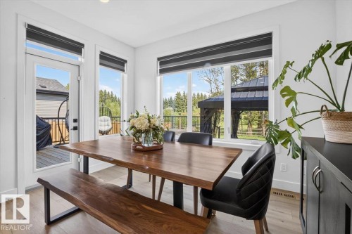 Hardwood-finish flooring throughout, bright white walls, and a glass-paneled door - 94 Harvest Crescent, Ardrossan, AB - Indoor Photo Showing Dining Room