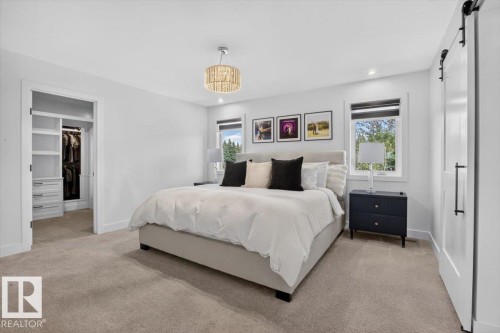 Recessed lighting, large windows, ceiling-mounted chandelier, built-in closet organization system, and a barn door - 94 Harvest Crescent, Ardrossan, AB - Indoor Photo Showing Bedroom