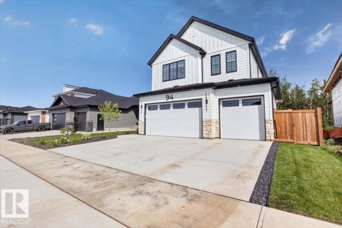 Contemporary exterior with vertical white siding, black-framed windows, and a two-car garage - 94 Harvest Crescent, Ardrossan, AB - Outdoor With Facade