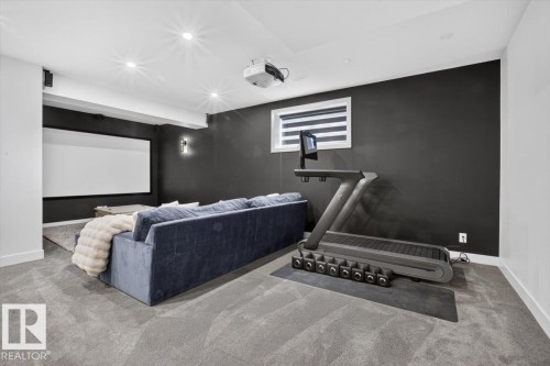 Projector screen, wall-mounted projector, wall sconce, recessed lighting, and grey carpeting - 94 Harvest Crescent, Ardrossan, AB - Indoor