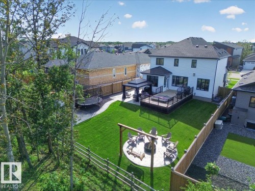 Expansive backyard with a manicured lawn, a gravel fire pit area, a multi-level deck, and a covered patio area - 94 Harvest Crescent, Ardrossan, AB - Outdoor With Deck Patio Veranda