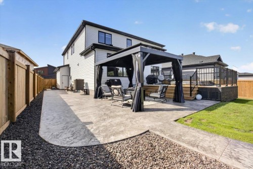 Stamped concrete patio, wooden privacy fence, elevated wooden deck with railing, detached shed, and a manicured lawn - 94 Harvest Crescent, Ardrossan, AB - Outdoor With Deck Patio Veranda With Exterior