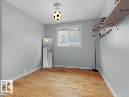 Hardwood-finish flooring with light-toned walls, featuring a window with white trim - #54 2131 Oak St, Sherwood Park, AB - Indoor Photo Showing Other Room