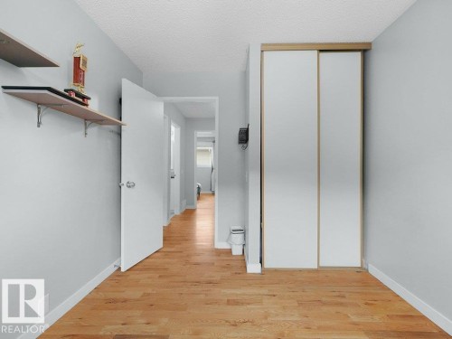 Wood-finish flooring, light grey wall paint, white sliding closet doors, white interior doors, and built-in shelving - #54 2131 Oak St, Sherwood Park, AB - Indoor Photo Showing Other Room