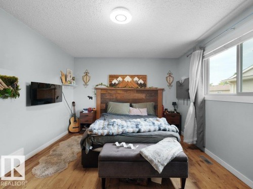 Hardwood-style flooring throughout, light gray wall paint, and ceiling-mounted lighting fixture - #54 2131 Oak St, Sherwood Park, AB - Indoor Photo Showing Bedroom