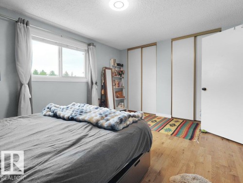 Recessed lighting, wood-finish flooring, white paneled doors, and two sliding closet doors - #54 2131 Oak St, Sherwood Park, AB - Indoor Photo Showing Bedroom