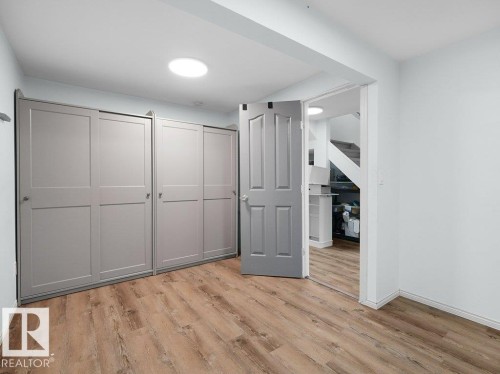 Wood-finish flooring with built-in storage cabinetry and a flush-mounted ceiling light - #54 2131 Oak St, Sherwood Park, AB - Indoor Photo Showing Other Room