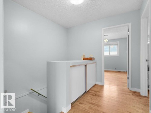 Light wood-finish flooring, built-in storage with sliding doors, and a flush mount ceiling light - #54 2131 Oak St, Sherwood Park, AB - Indoor Photo Showing Other Room