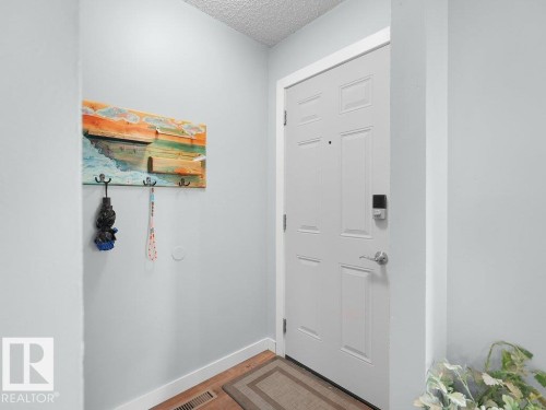 White paneled door with smart lock, wood-finish flooring, and light gray wall paint - #54 2131 Oak St, Sherwood Park, AB - Indoor Photo Showing Other Room