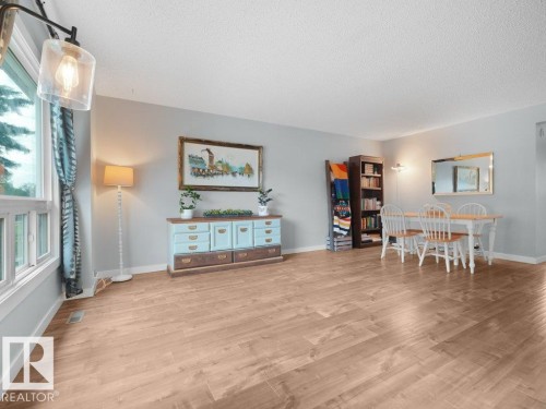 Light wood-finish flooring throughout, bright window with white trim, and light gray wall paint - #54 2131 Oak St, Sherwood Park, AB - Indoor