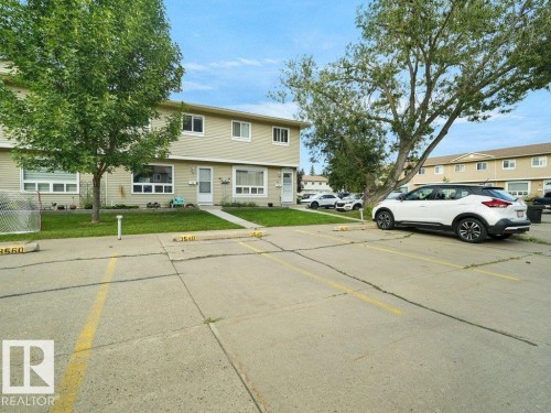 Two-story residential building with light-colored siding, multiple windows, and a paved parking area - #54 2131 Oak St, Sherwood Park, AB - Outdoor