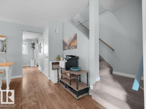 Wood-finish flooring throughout, with a carpeted staircase featuring a wood handrail - #54 2131 Oak St, Sherwood Park, AB - Indoor