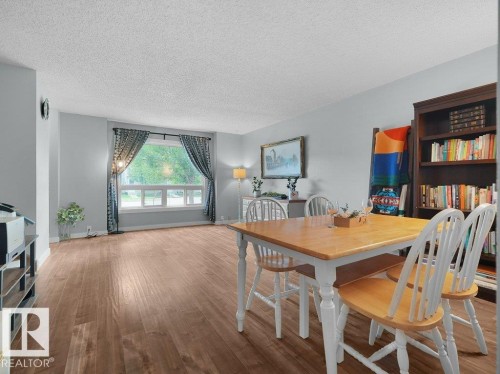 Spacious room featuring wood-finish flooring, light grey wall paint, and a large multi-pane window - #54 2131 Oak St, Sherwood Park, AB - Indoor Photo Showing Dining Room
