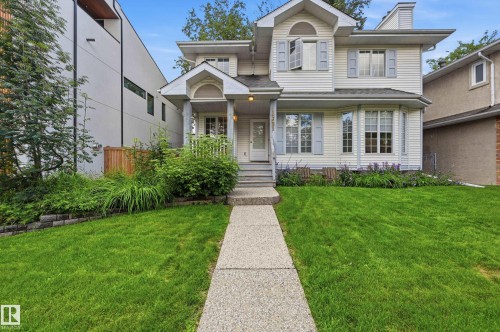 Exterior featuring light-colored siding, multiple gabled rooflines, a covered front porch, and a bay window with decorative shutters - 14631 Summit Drive Nw, Edmonton, AB 