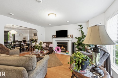 Living area featuring wood-finish flooring, recessed lighting, and a corner fireplace with a white mantel and tile surround - 14631 Summit Drive Nw, Edmonton, AB 