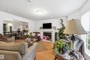 Living area featuring wood-finish flooring, recessed lighting, and a corner fireplace with a white mantel and tile surround - 14631 Summit Drive Nw, Edmonton, AB 