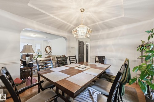 Dining area with a coffered ceiling, chandelier, and a wide arched opening - 14631 Summit Drive Nw, Edmonton, AB 
