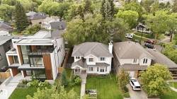 White traditional exterior with a front bay window, gabled roof, and a mature treed lot - 
