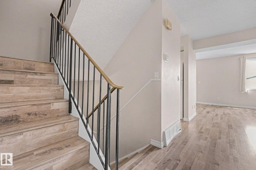 Staircase featuring wood-finish treads and risers, black metal balusters, and a brass-tone handrail - 1096 Knottwood Road Nw, Edmonton, AB - Indoor Photo Showing Other Room