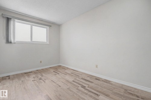 Room with light wood-finish flooring, white walls, and a white window frame with blinds - 1096 Knottwood Road Nw, Edmonton, AB - Indoor Photo Showing Other Room